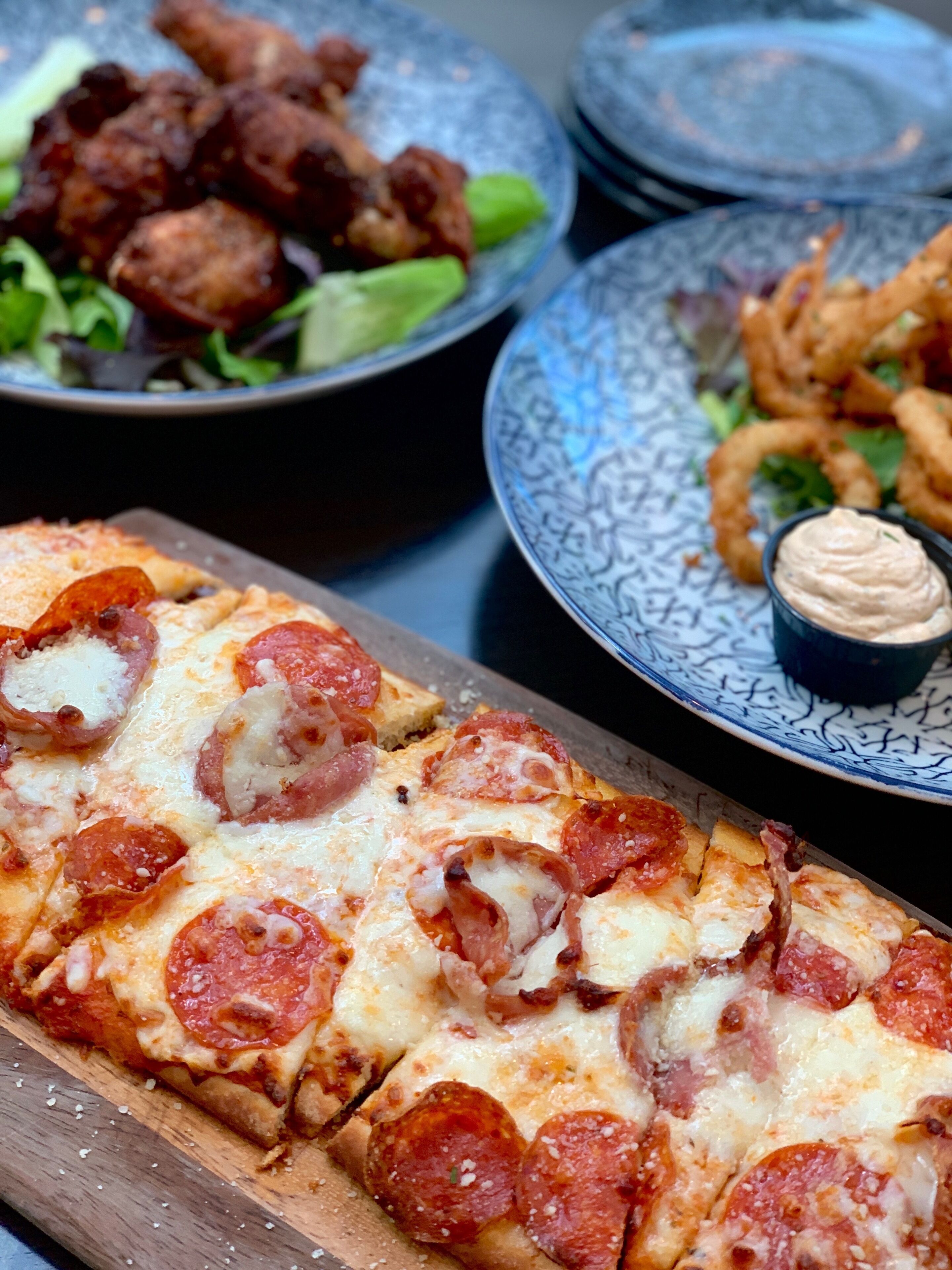 Una mesa con una variedad de platos, incluyendo pizza, ensalada y comida frita.