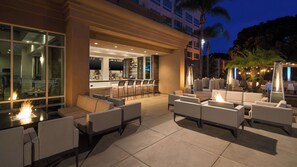 An outdoor seating area with fire pits, bar, and lounge chairs.
