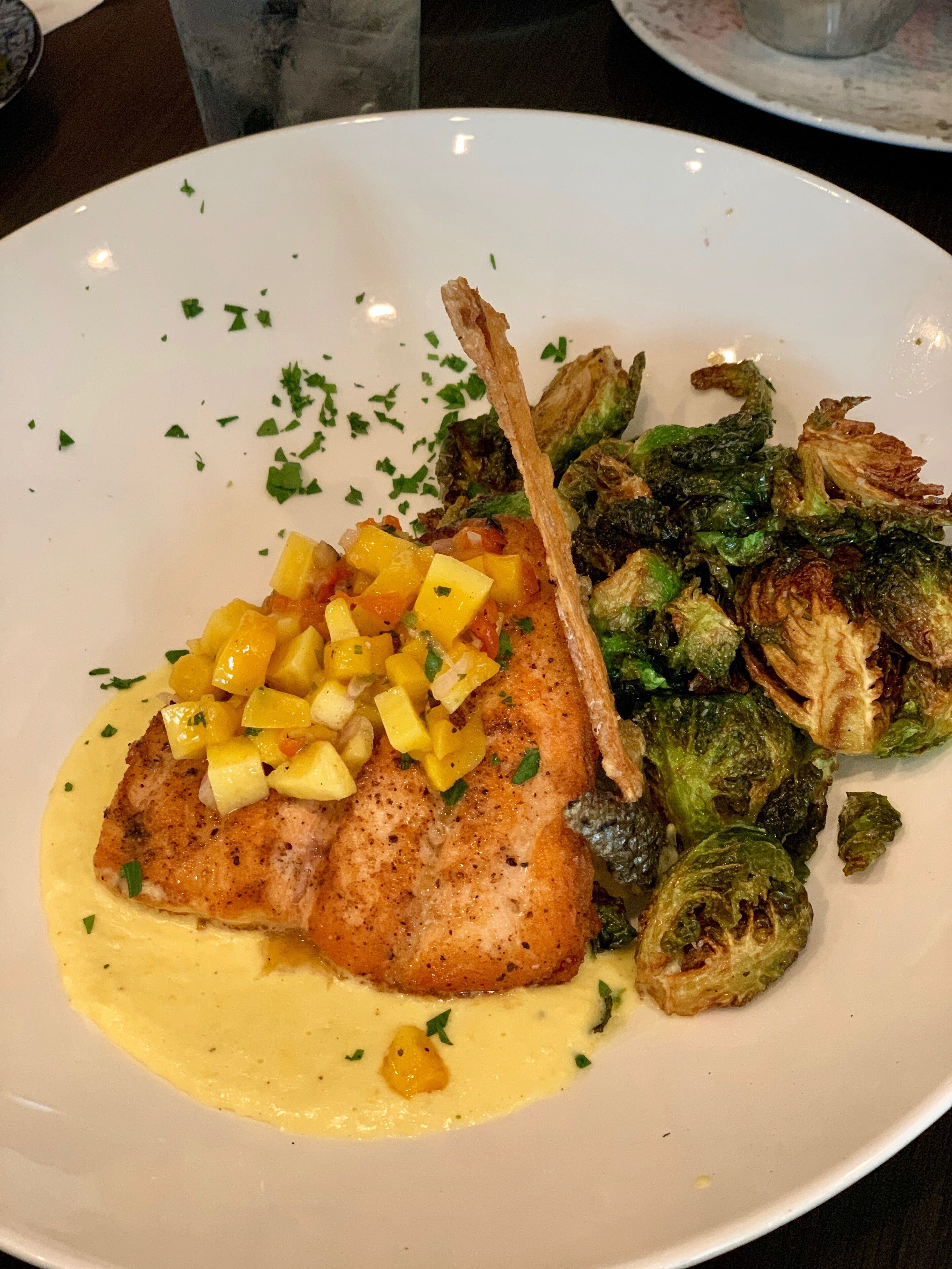 Ein Teller mit Fisch, gerösteten Rosenkohl und Mangosalsa.