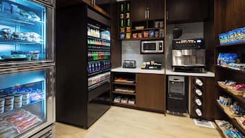 Un punto de autoservicio con bebidas frías, aperitivos y una máquina de café.