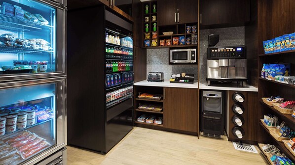A self-service food and beverage station with refrigerated drinks, snacks, and a coffee machine.