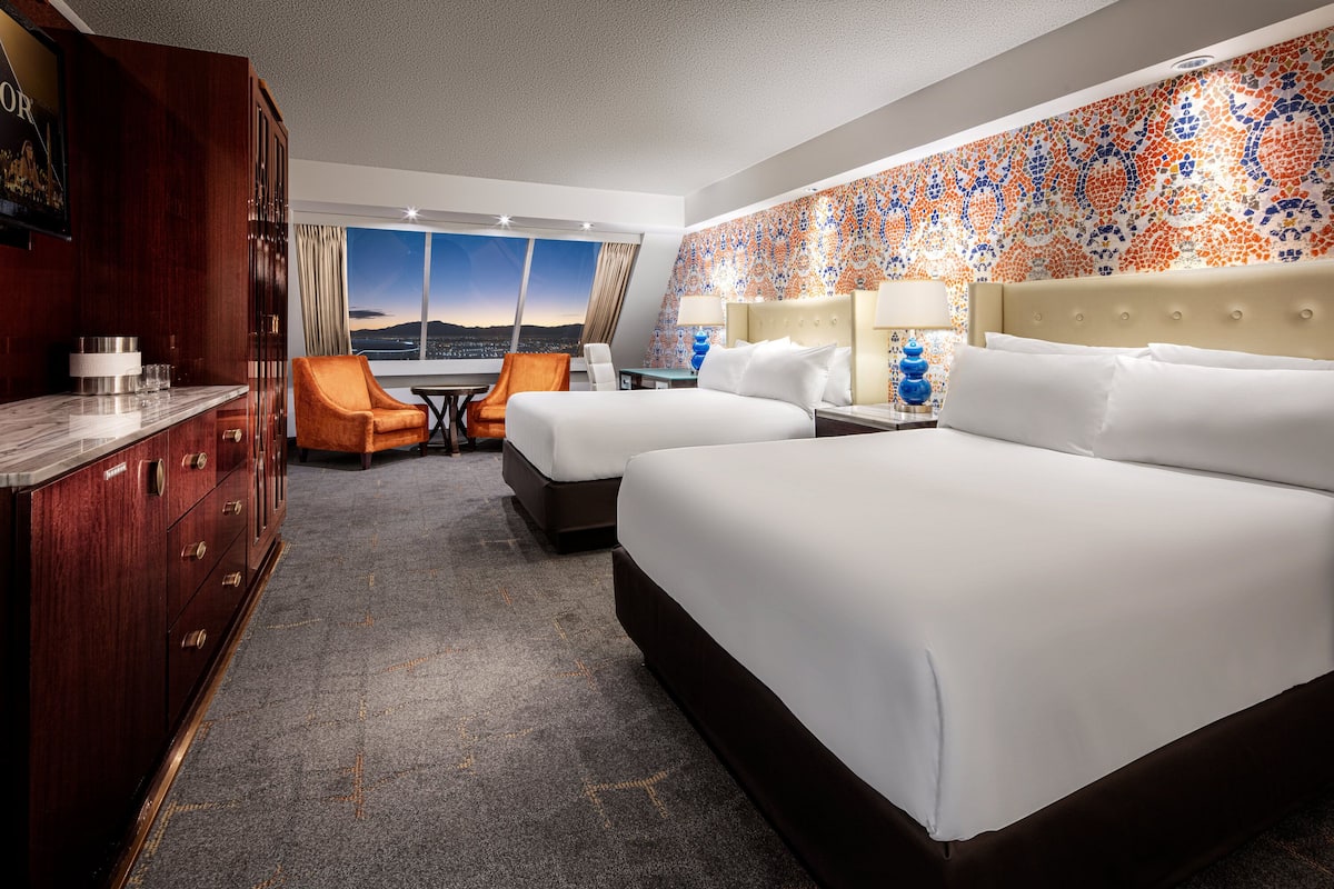 Une chambre d’hôtel avec un grand lit, un bureau, une chaise et une vue sur la ville.