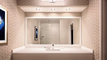 A bathroom with a large mirror, a sink, and a shower area.