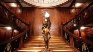 A grand staircase with ornate woodwork and a statue at the top.