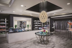 Un interior moderno con una mesa redonda central, una lámpara decorativa y estantes llenos de productos.