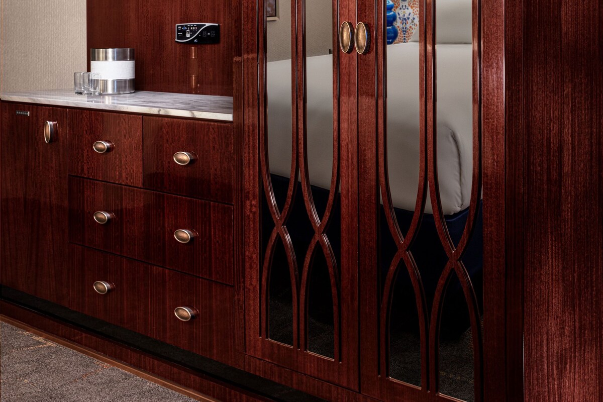 Une armoire en bois avec des portes miroir et un téléviseur intégré au-dessus.