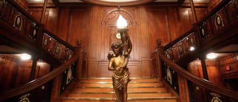 Una imponente escalera con detalles de madera decorativos y una estatua en la parte superior.