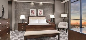 Une chambre d’hôtel moderne avec un grand lit, deux tables de chevet avec des lampes, une commode en bois, un banc et une vue sur la ville par une grande fenêtre.