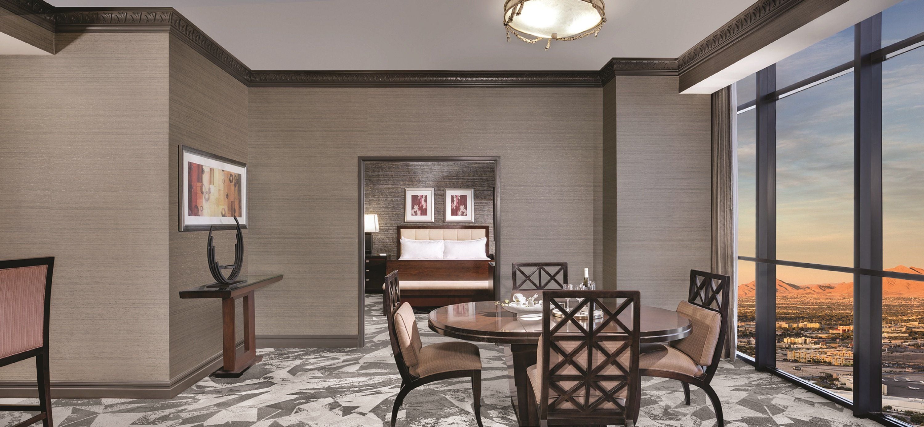 Une chambre d’hôtel comprenant un coin repas, un lit et une grande fenêtre donnant sur la ville.