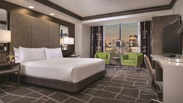 Une chambre d’hôtel avec un grand lit, un bureau, deux chaises, une télévision et une vue sur la ville.