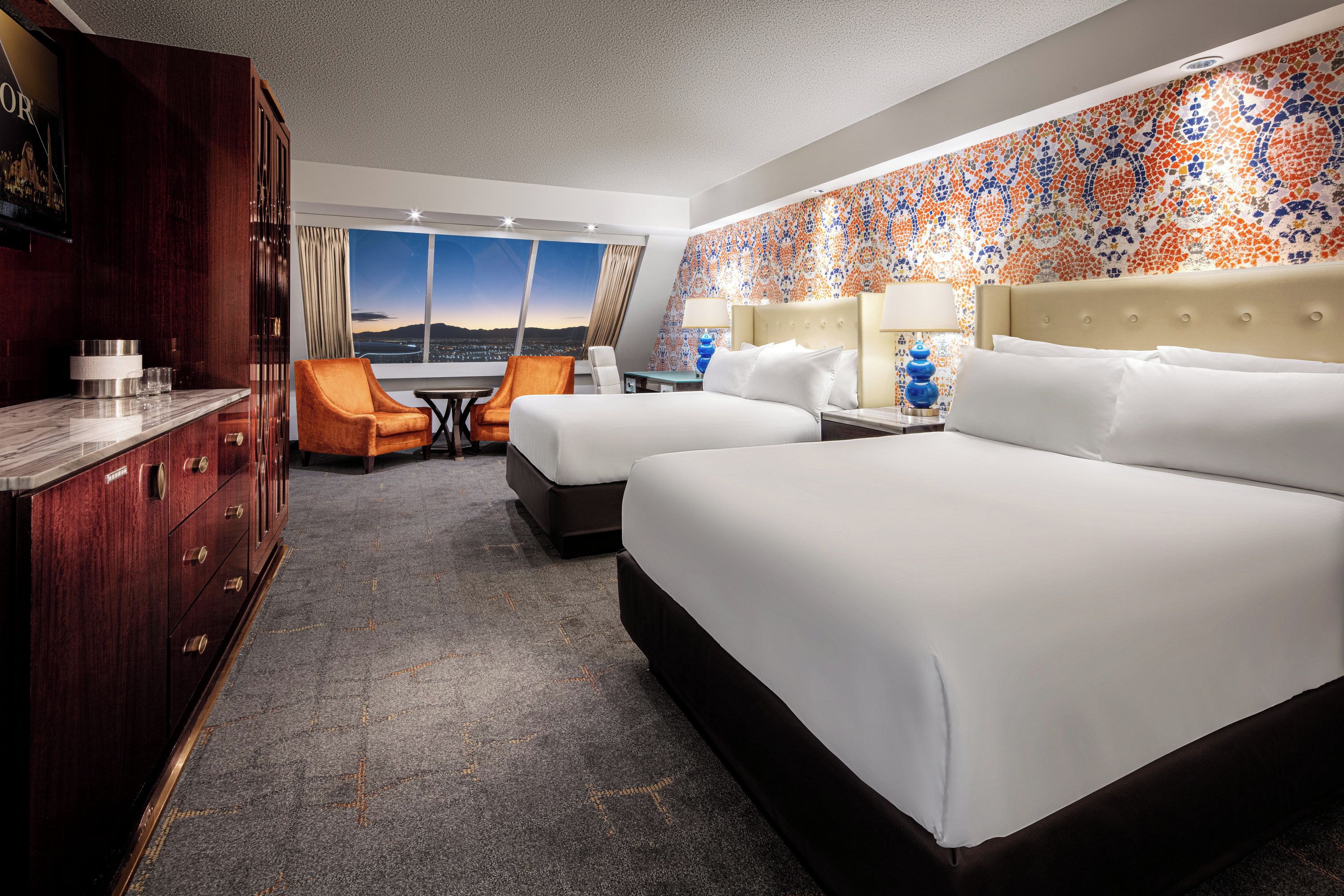 Habitación de hotel con una cama grande, un escritorio, una silla y vistas a la ciudad.