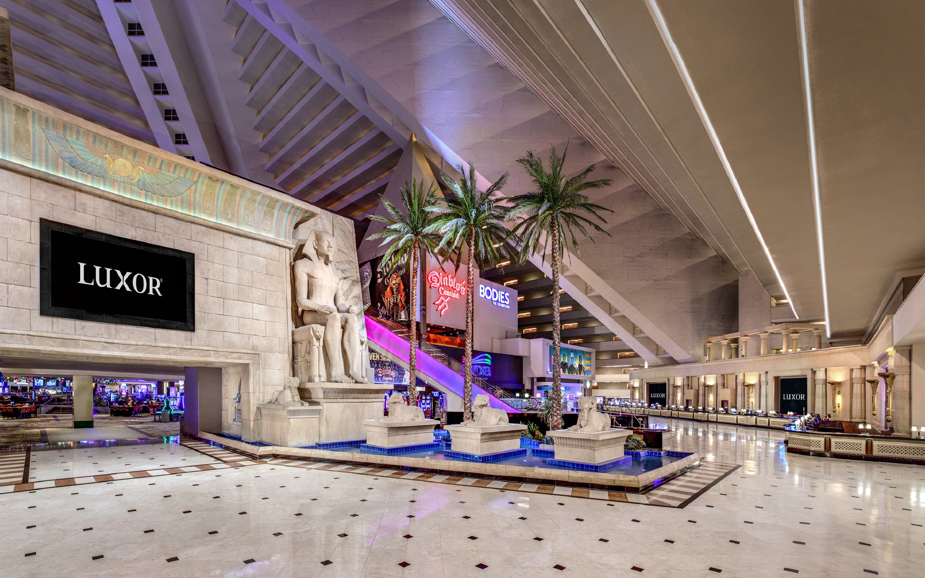 A spacious atrium with a central fountain, a Luxor store, and a sign for the Bodies exhibition.