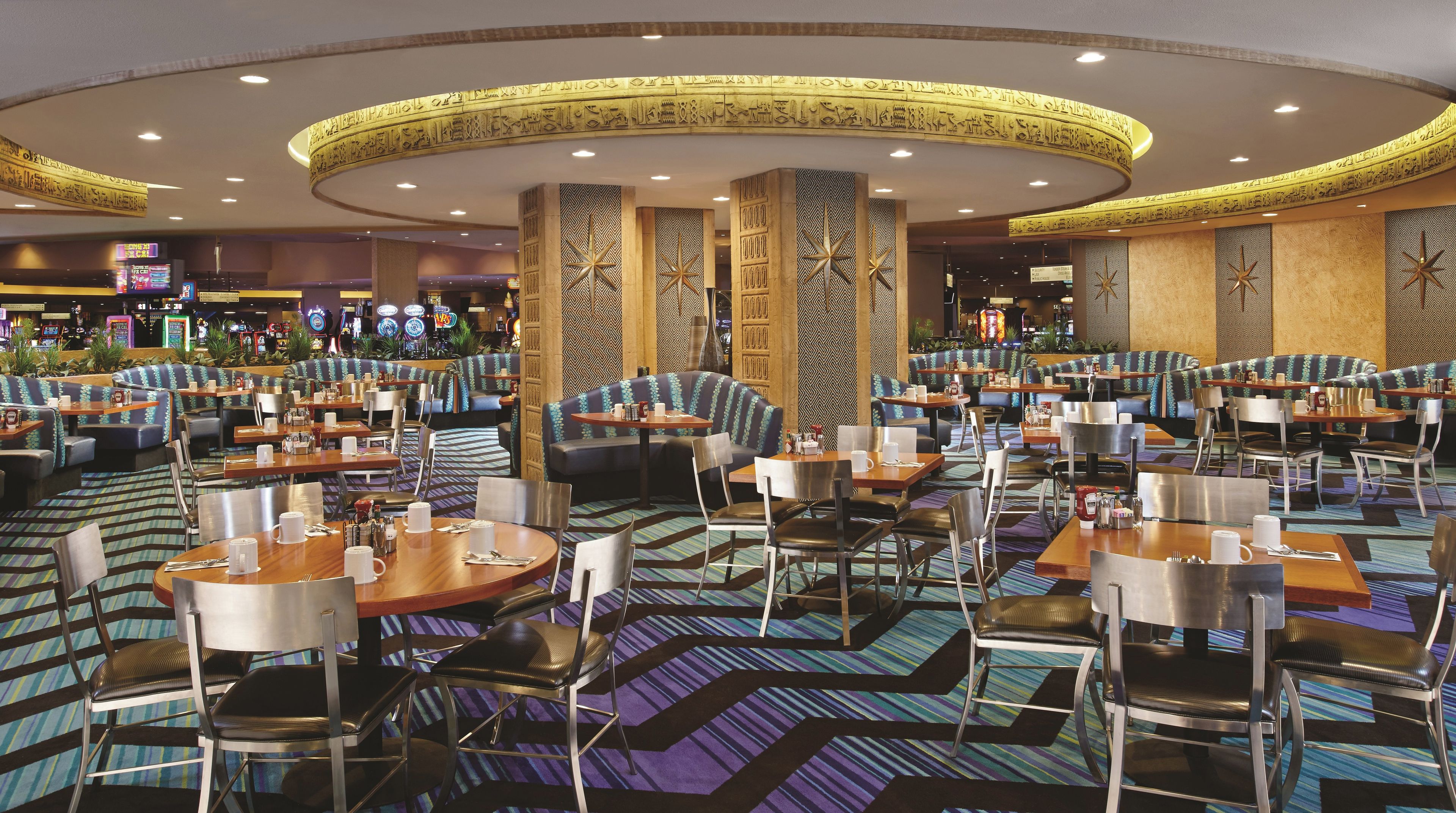 Un restaurant spacieux doté de plusieurs espaces de restauration, notamment des banquettes et des tables, ainsi qu’une moquette à motifs.