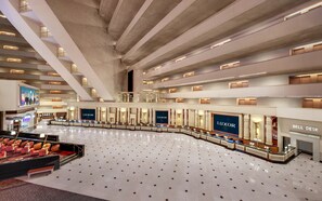 Un hall d’entrée spacieux avec un espace salon central, plusieurs niveaux et un grand panneau lumineux portant l’inscription LUXOR.