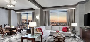 A modern hotel room with a large sofa, a dining table, and a TV. - Luxor Hotel and Casino (Las Vegas)