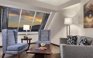 Habitación de hotel con dos sillones, un sofá, una mesa de centro, una lámpara y un cuadro.