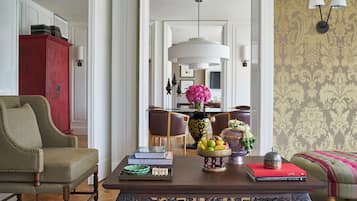 A living room with a wooden coffee table, a red cabinet, a green armchair, and a patterned wallpaper.