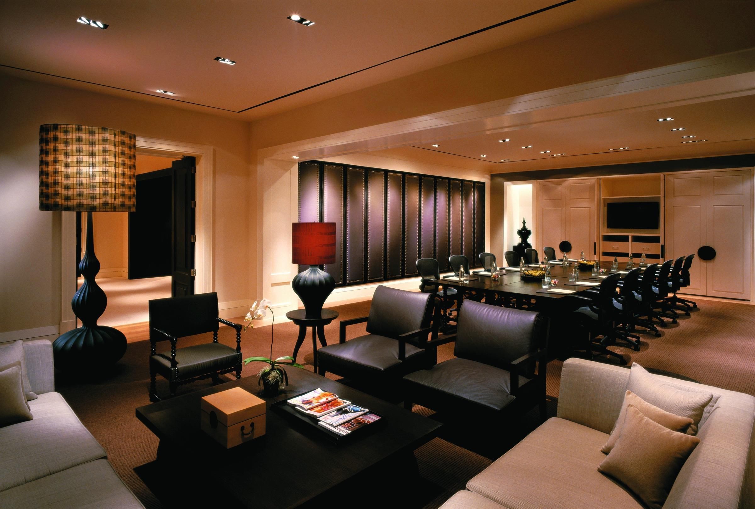 A conference room with a long table, multiple chairs, and a television.