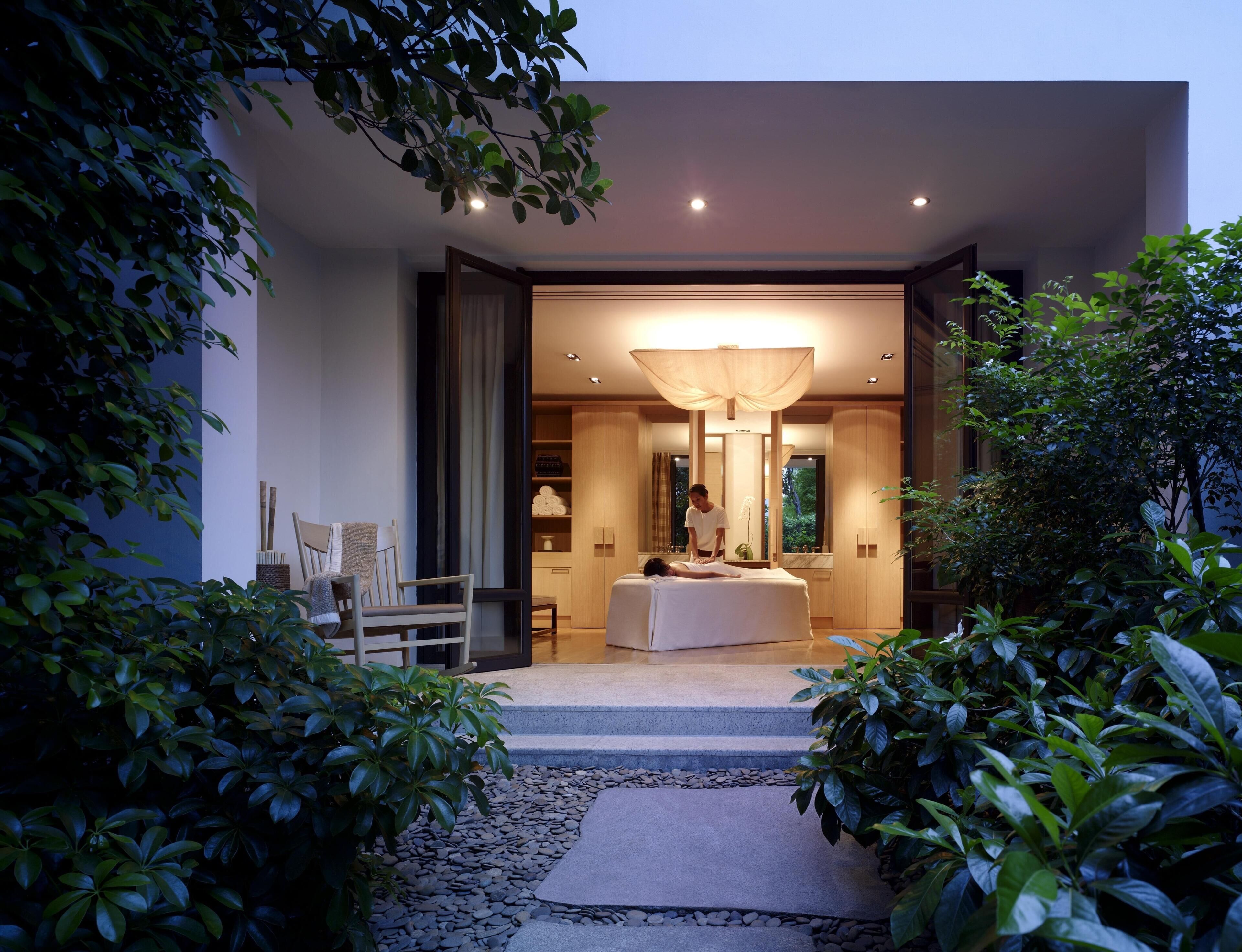 A modern spa with a massage table, a large mirror, and a well-lit entrance.
