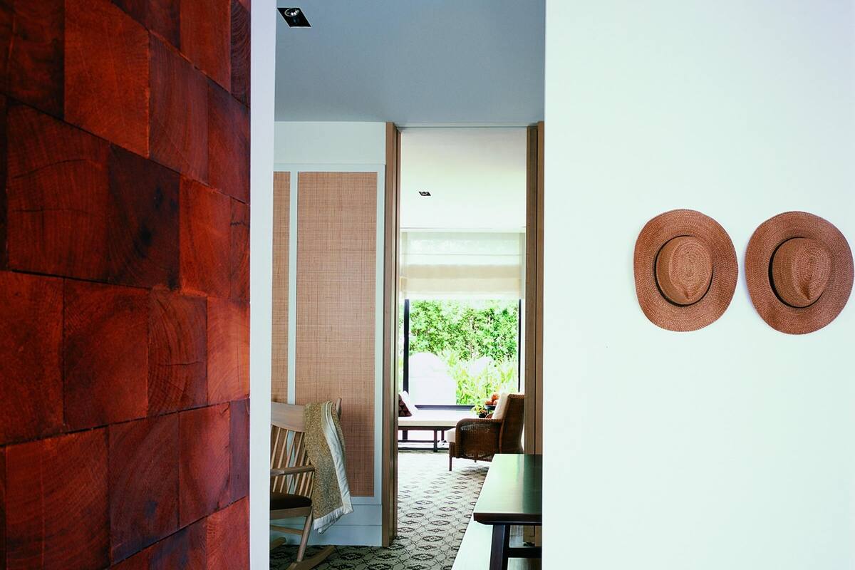 Una habitación con pared de madera, una cesta tejida con objetos, un comedor con mesa y sillas, y una vista por la ventana.