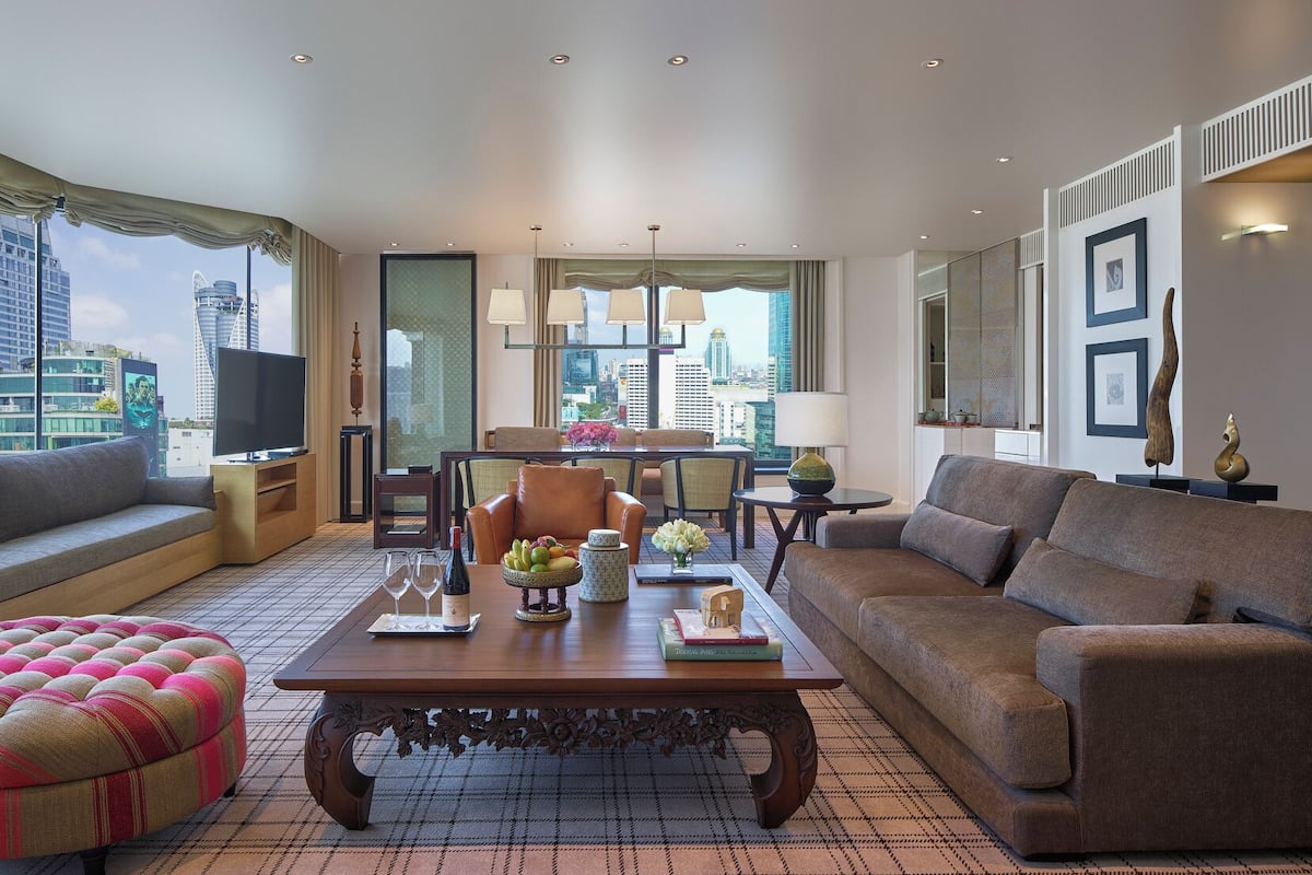 Una sala de estar moderna con un sofá, un sillón, una mesa de centro y vistas a la silueta urbana.