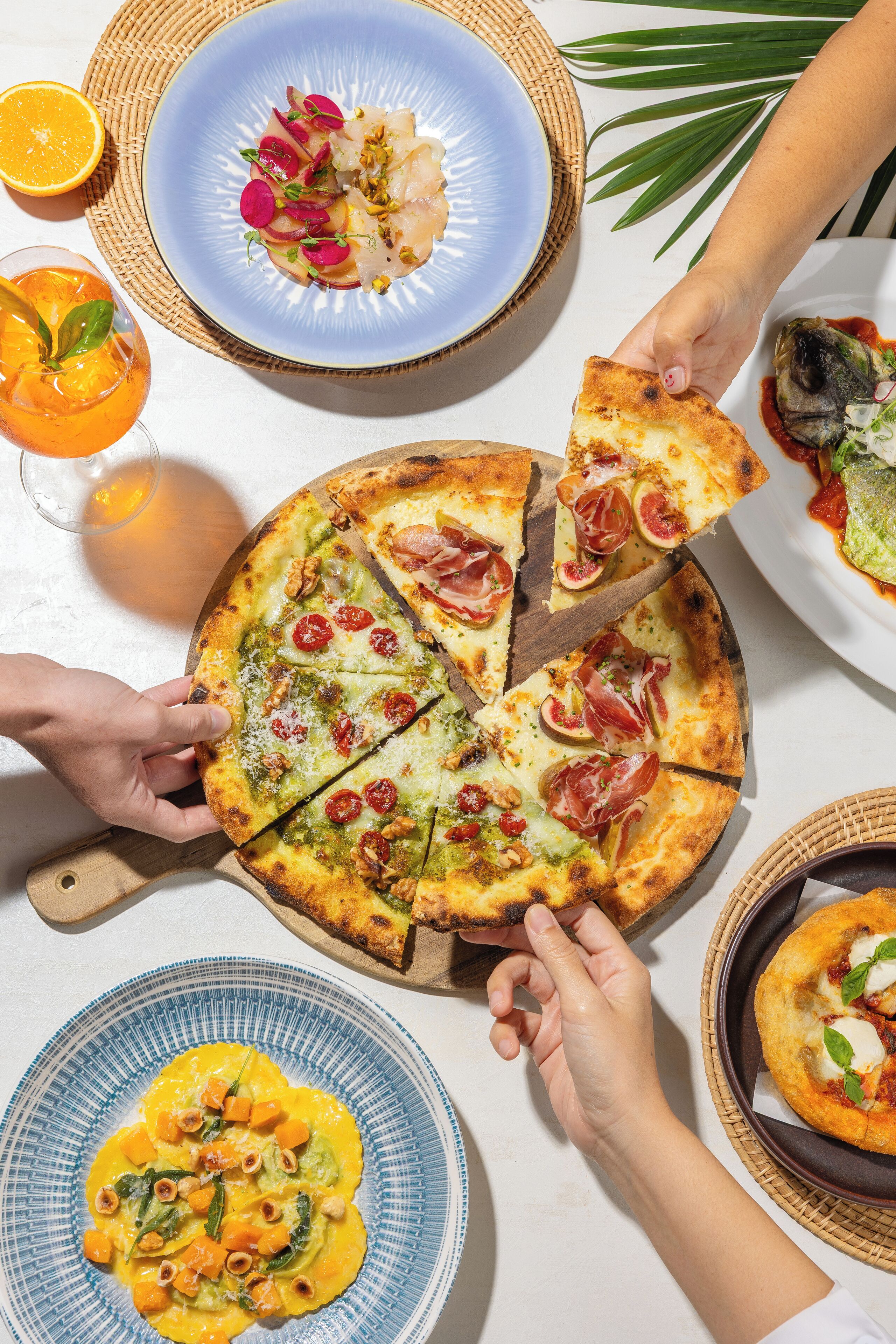 A pizza with various toppings, a plate of food, and a drink.