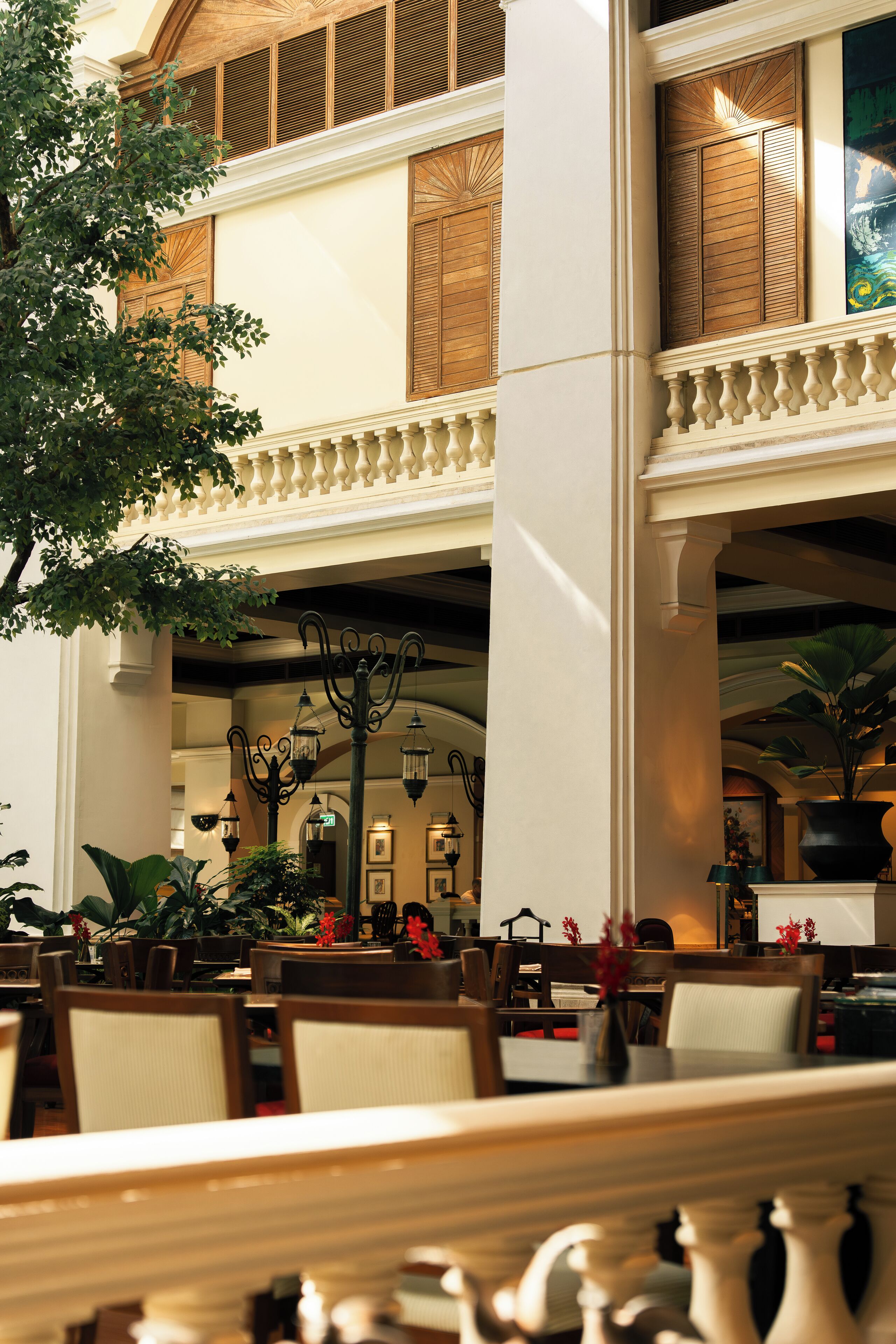A hotel lobby with a high ceiling, ornate columns, and a seating area with tables and chairs.
