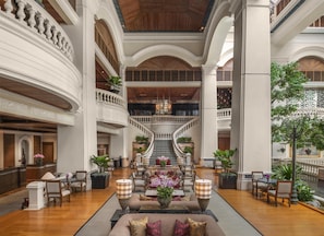 A grand lobby with a central staircase, multiple seating areas, and a fountain.