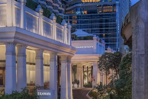 A grand entrance with columns, a sign for Grand Hyatt, and a modern building in the background.
