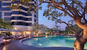 Una piscina al aire libre, sombrillas, sillones reclinables de piscina