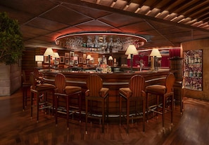 A bar area with wooden chairs, a bar counter, and a circular ceiling design.