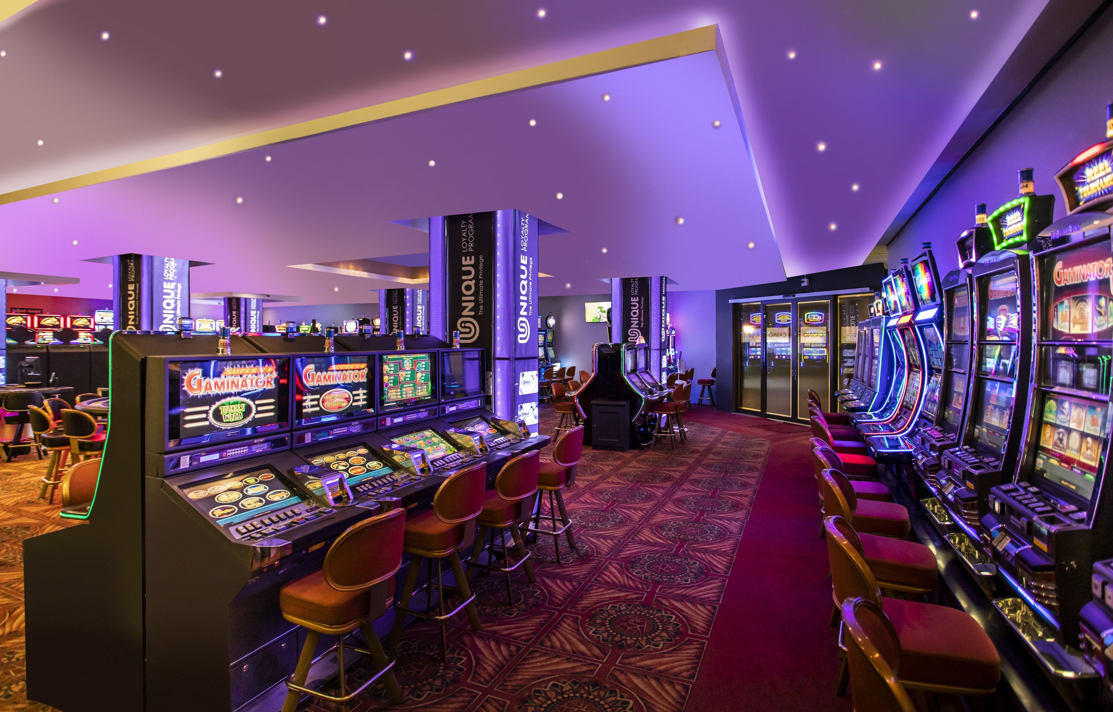 Ein Casino mit mehreren Spielautomaten und einem Teppichboden.