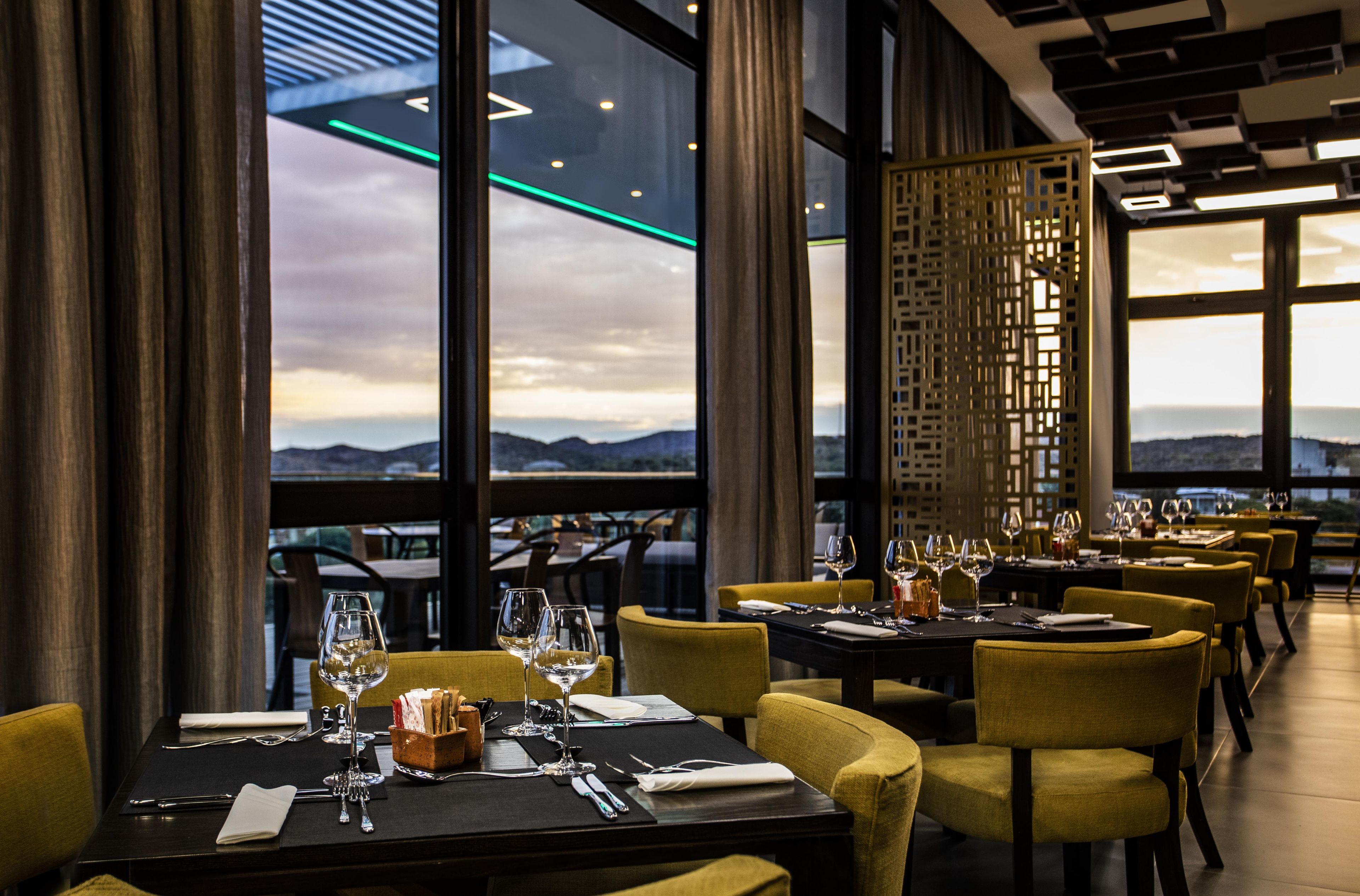 A restaurant with tables set for dining, large windows offering a view of the mountains, and a modern interior design.