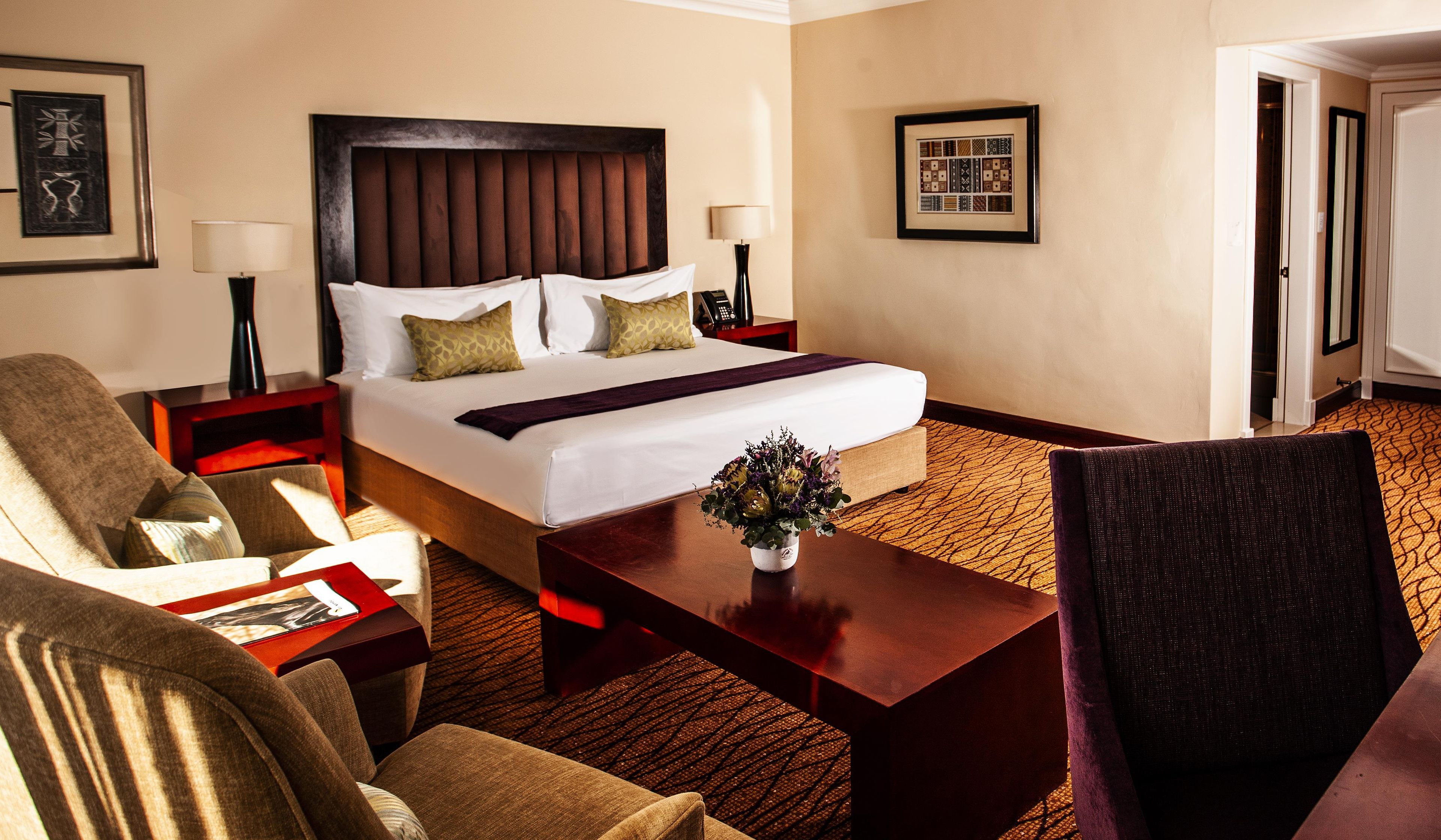 Ein Hotelzimmer mit einem großen Bett, zwei Nachttischen, einem Schreibtisch, einem Sessel und einem Teppichboden.