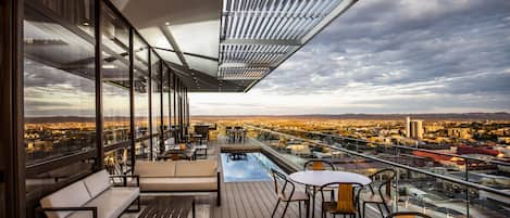 A modern outdoor terrace with a pool, seating, and a city view.