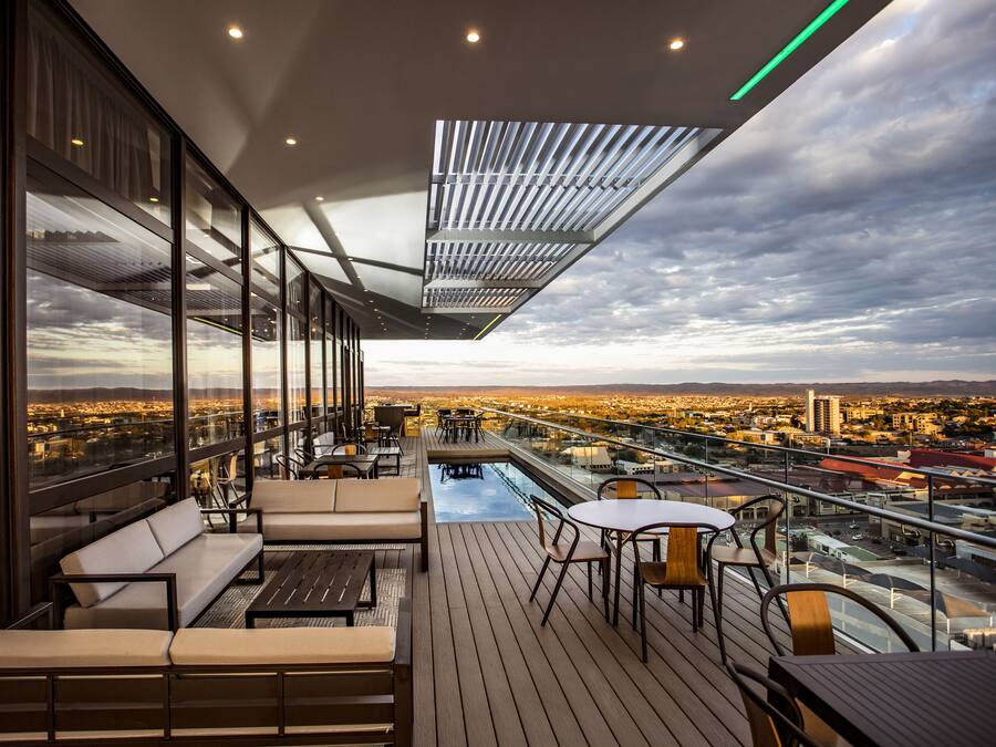Una terraza moderna al aire libre con piscina, mobiliario y vistas a la ciudad.