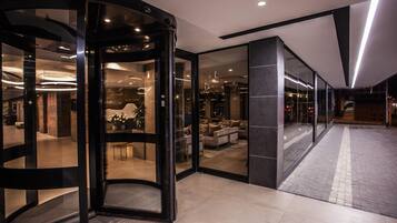 A hotel lobby with a revolving door, a seating area with sofas, and a reception desk.