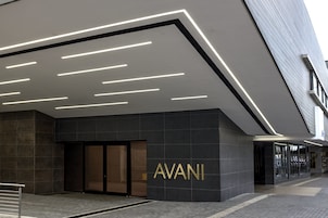 Una entrada moderna de edificio con un llamativo letrero 'AVANI', un diseño de iluminación elegante y un estilo arquitectónico contemporáneo y limpio.