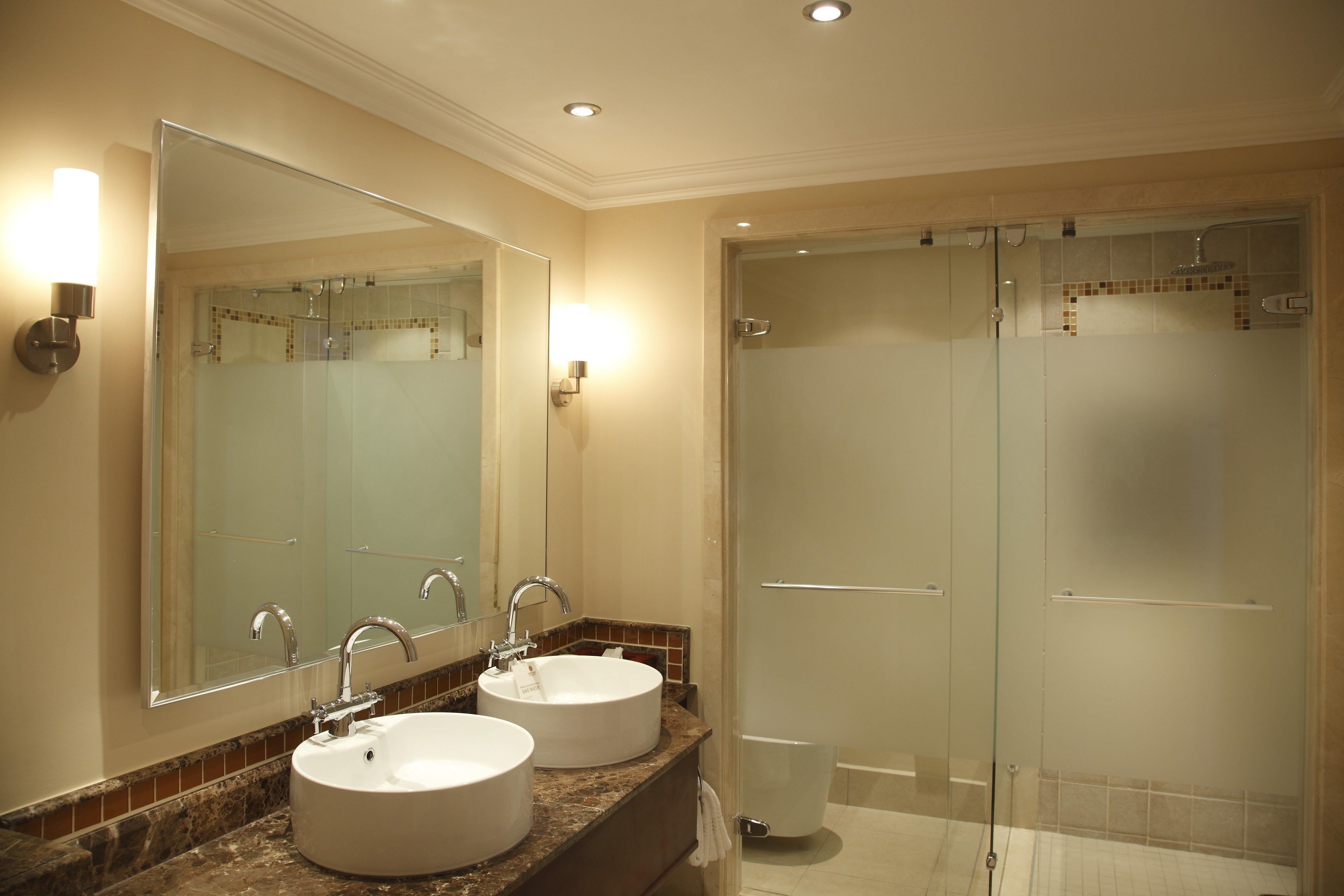 A bathroom with two sinks, a large mirror, and a glass-enclosed shower area.