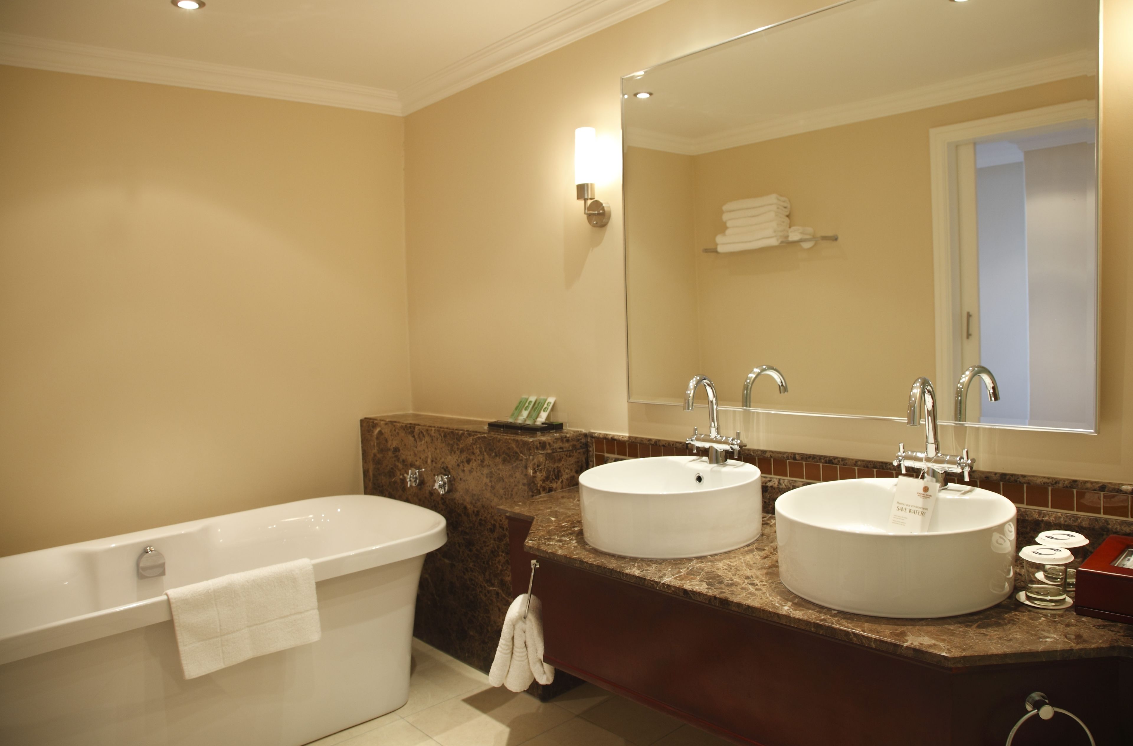 A bathroom with a bathtub, two sinks, and a large mirror.