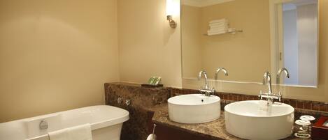 A bathroom with a bathtub, two sinks, and a large mirror.