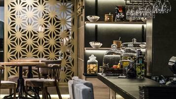 Un espace bar moderne avec des tabourets, un comptoir avec de la verrerie et des bocaux décoratifs.