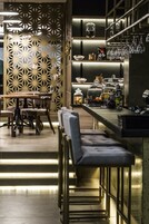 Un área de bar moderna con taburetes, una barra con cristalería y frascos decorativos.