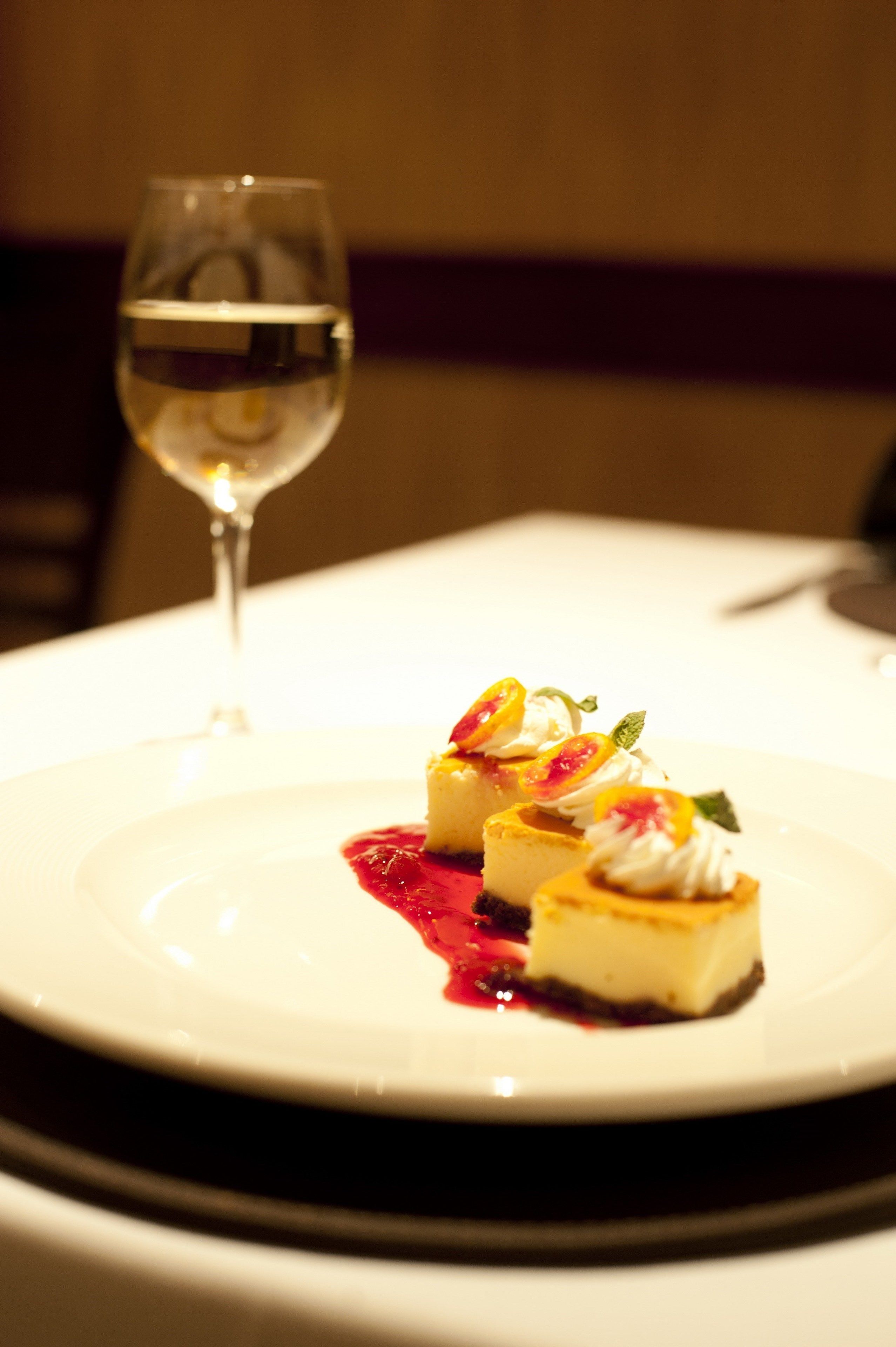 Un plato de postre con una copa de vino blanco sobre una mesa.