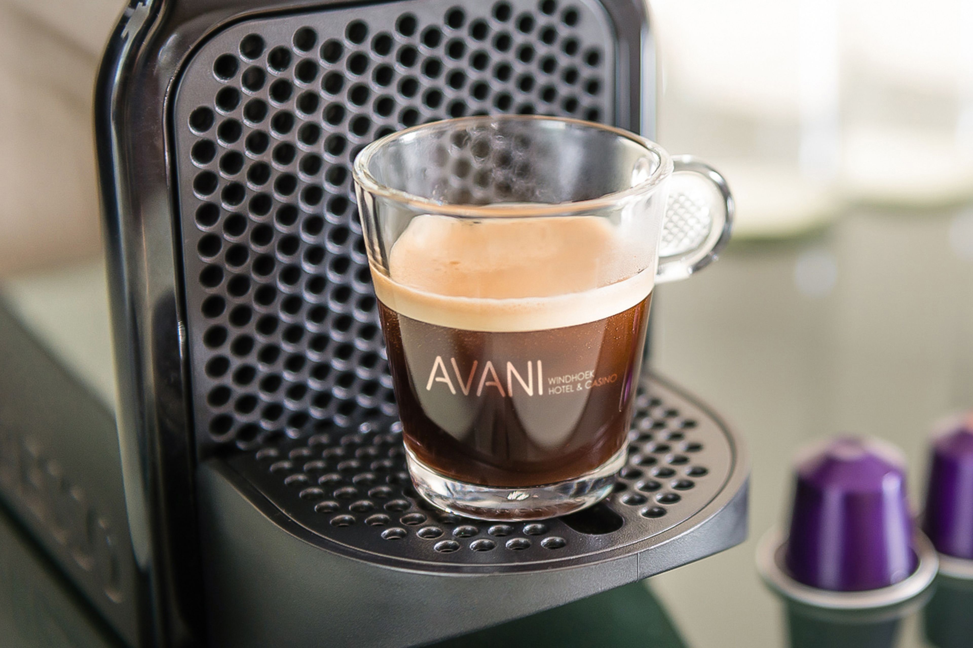 A coffee machine with a glass cup labeled "AVANI" on its drip tray.
