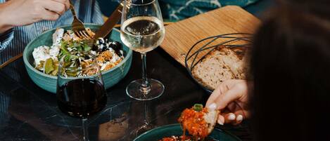 A dining table with a salad, a bowl of soup, and a plate with eggs and sauce. There are wine glasses and cutlery on the table.
