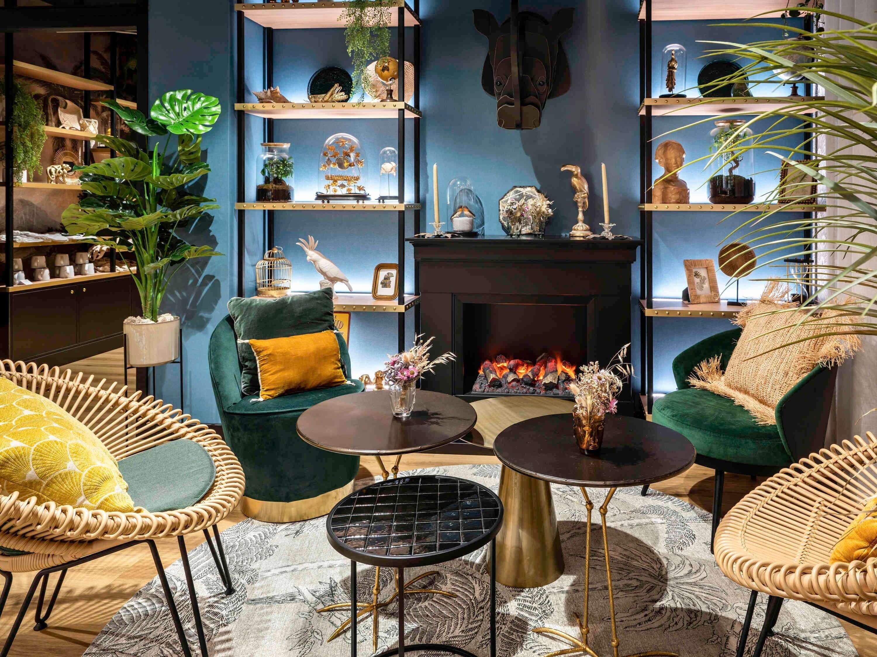 A cozy living room with a fireplace, green armchairs, and a variety of decorative items on shelves.