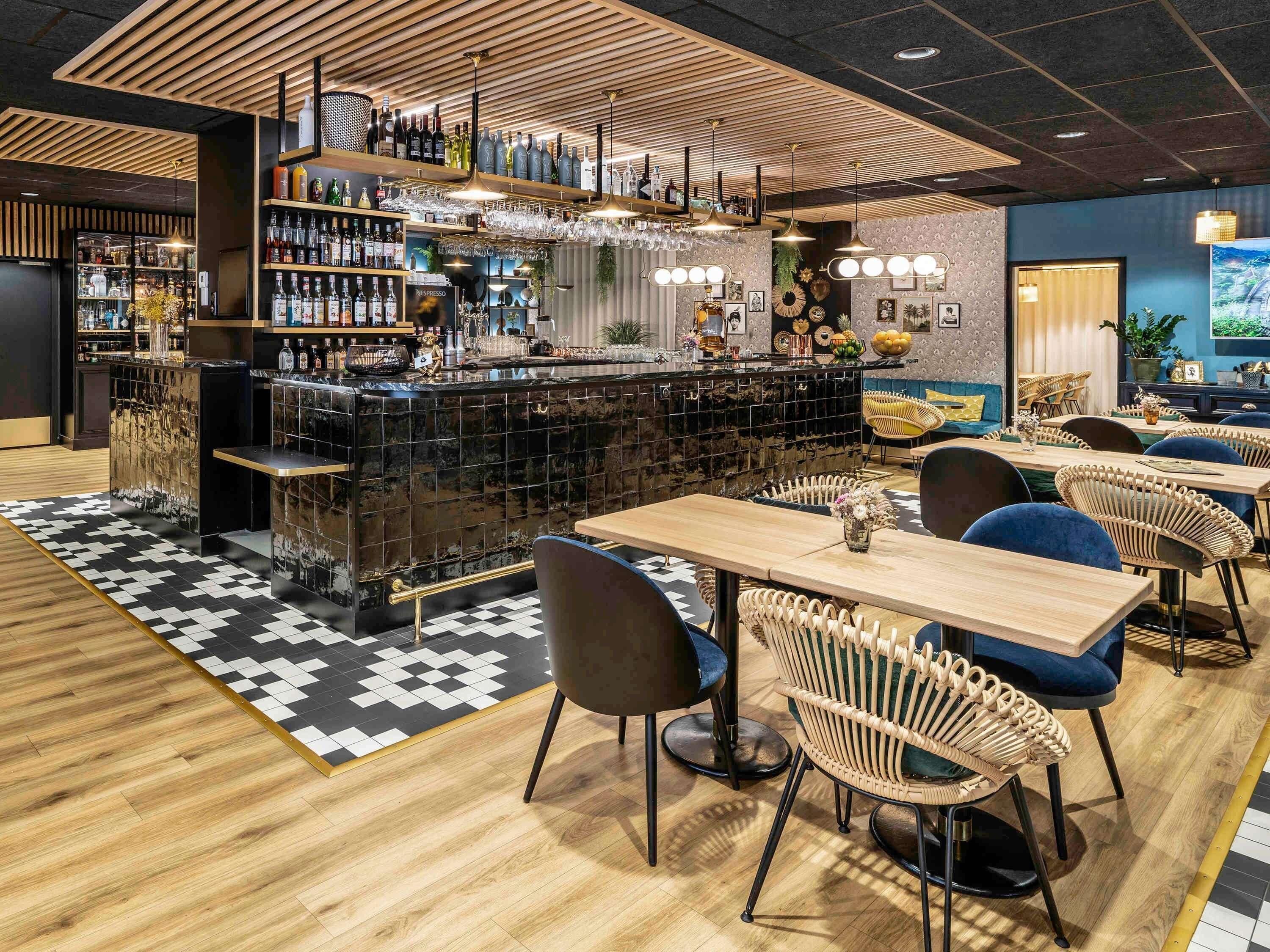 A bar area with a checkered floor, wooden furniture, and a variety of bottles and glasses.