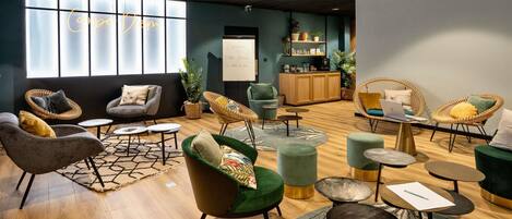 Een moderne loungehoek met zitplaatsen, een houten kast en een projectiescherm.