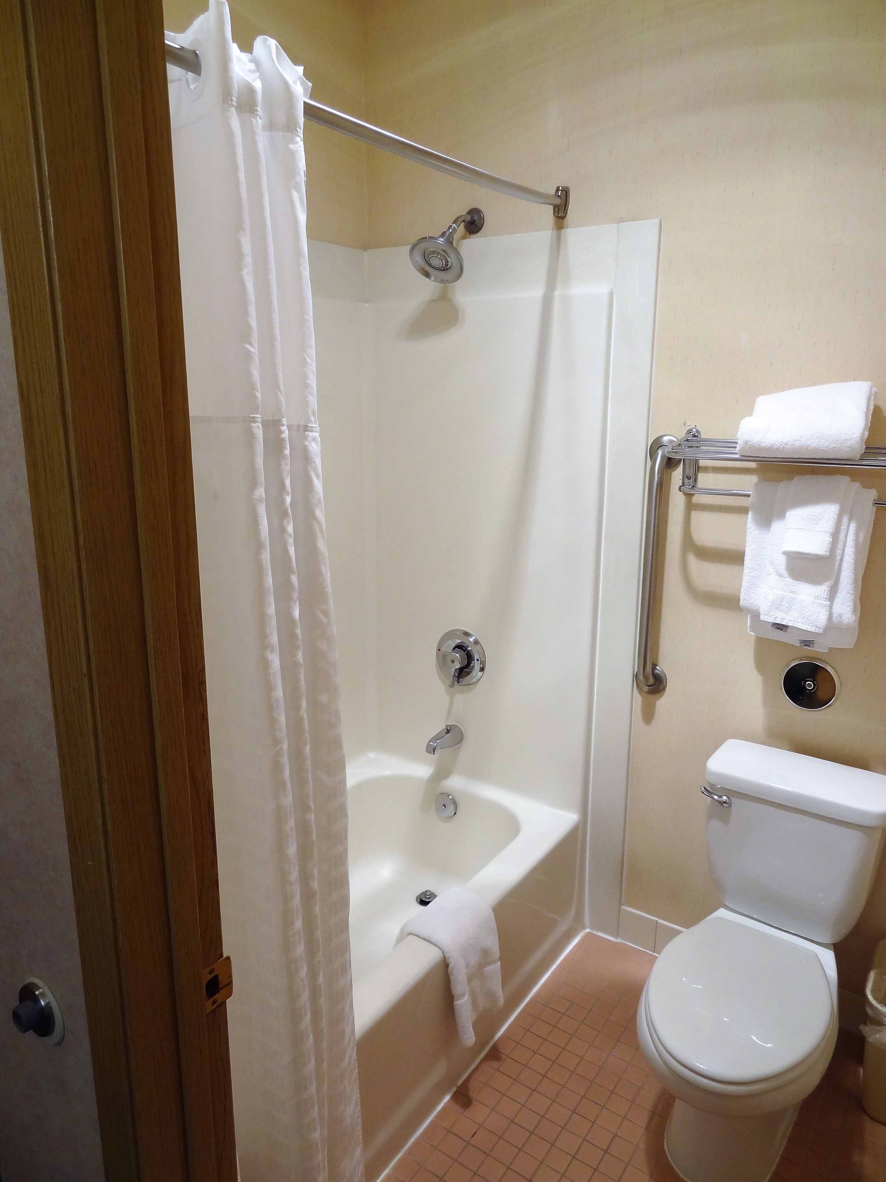 A bathroom with a shower, a bathtub, a toilet, and a towel rack.
